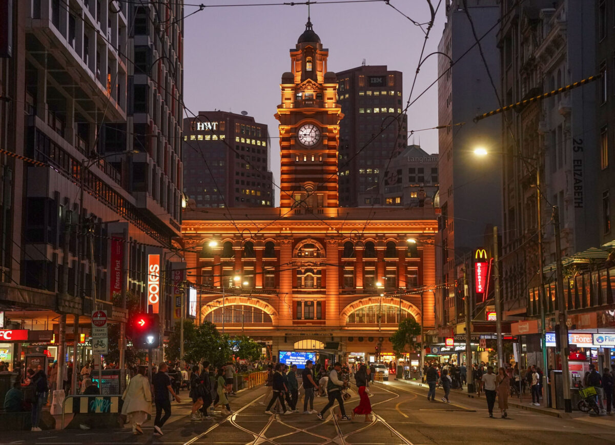 Wide shot of Flinders Street Station from Elizabeth St, with people walking.